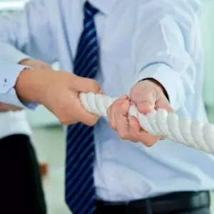 Two business people engaged in a collaborative tug-of-war.