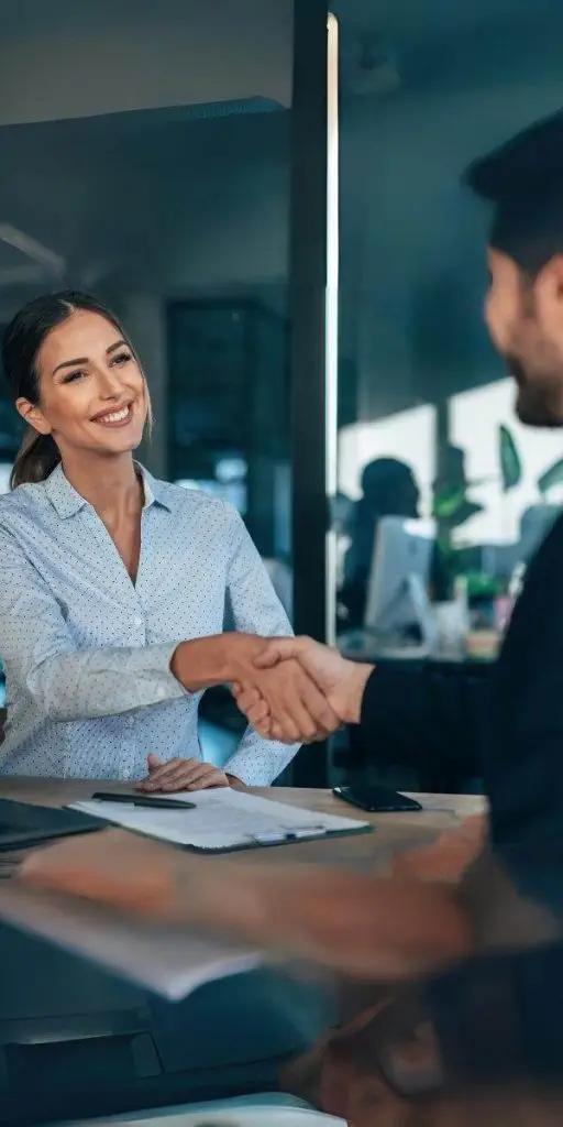 A man and woman shaking hands in an office. A man and woman shaking hands in an office.
