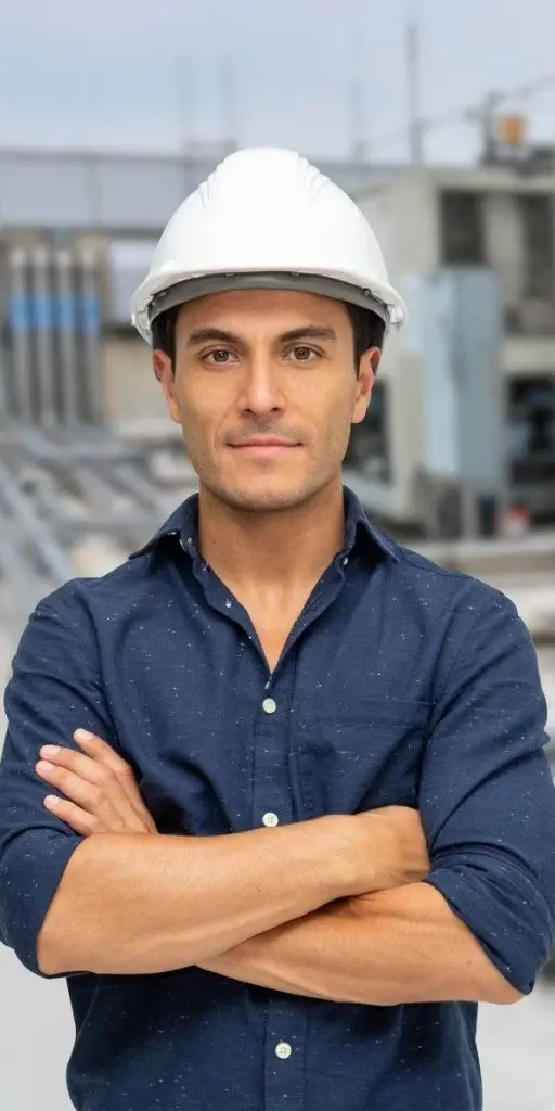 A man in a hard hat standing in front of a building. A man in a hard hat standing in front of a building.