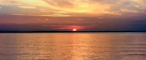 The sun is setting over a body of water. The sun is setting over a body of water.