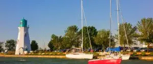 Two sailboats docked in the water near a lighthouse. Two sailboats docked in the water near a lighthouse.