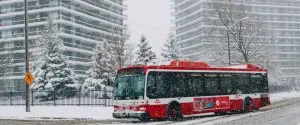 A red and white bus driving down a snowy street. A red and white bus driving down a snowy street.